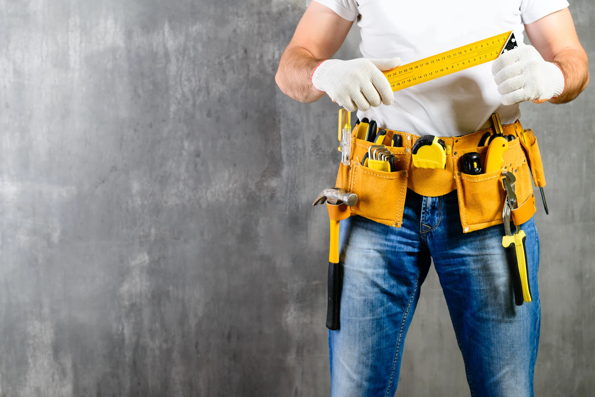 Wallpaper image of a handyman holding a measuring meter with his tools bearing in the waistbelt.